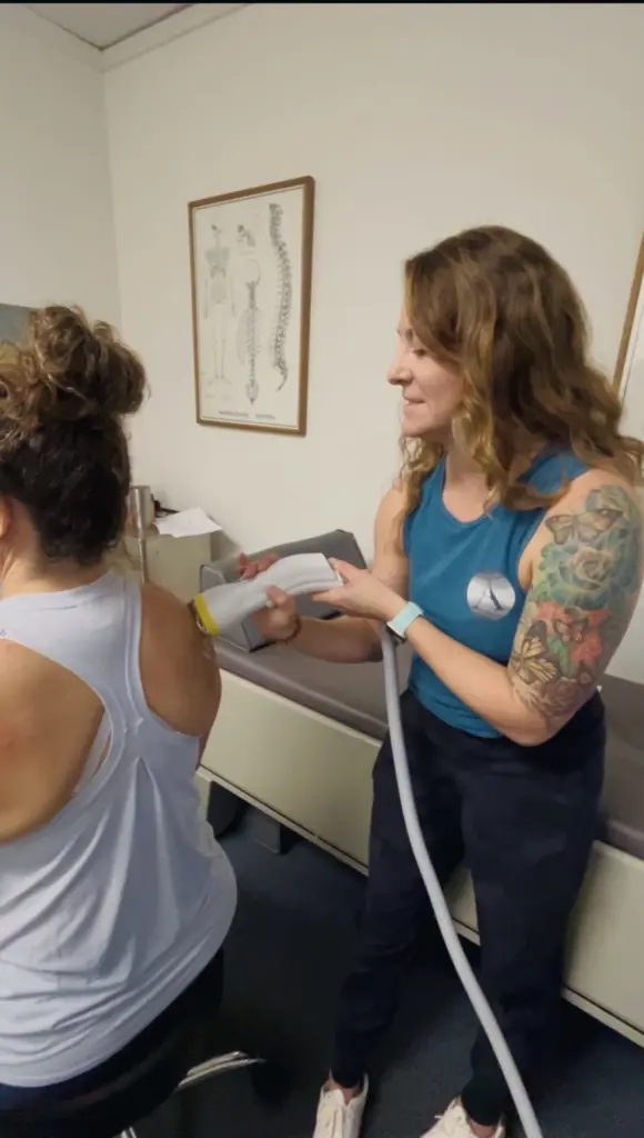 A practitioner treats a patient’s shoulder with the SoftWave applicator in a treatment room at Aptos Chiropractic.